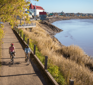 residents biking along Riverfront Trail in Moncton with Dieppe in the background