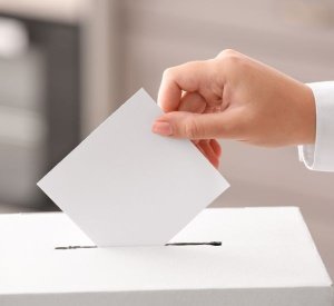Hand dropping a ballot into a box