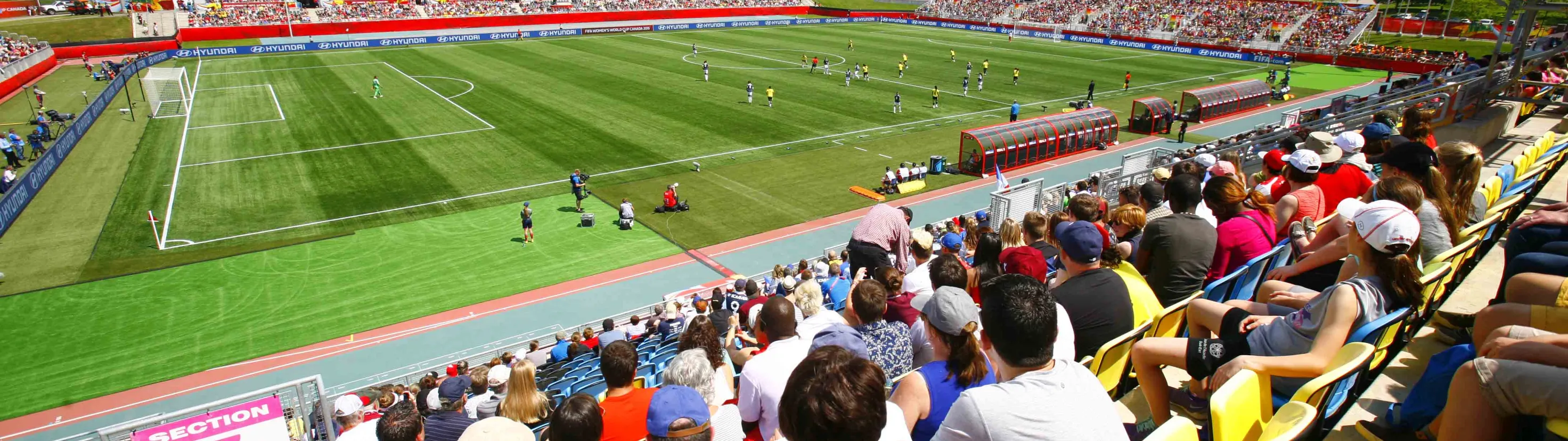 A crowd of people in the stands of a stadium watching a soccer match