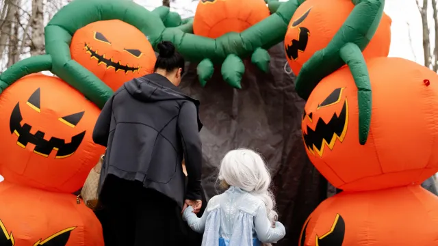 Mother and daughter passing under a blown up pumpkin arch at the zoo