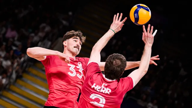 Two male volleyball players mid-volley