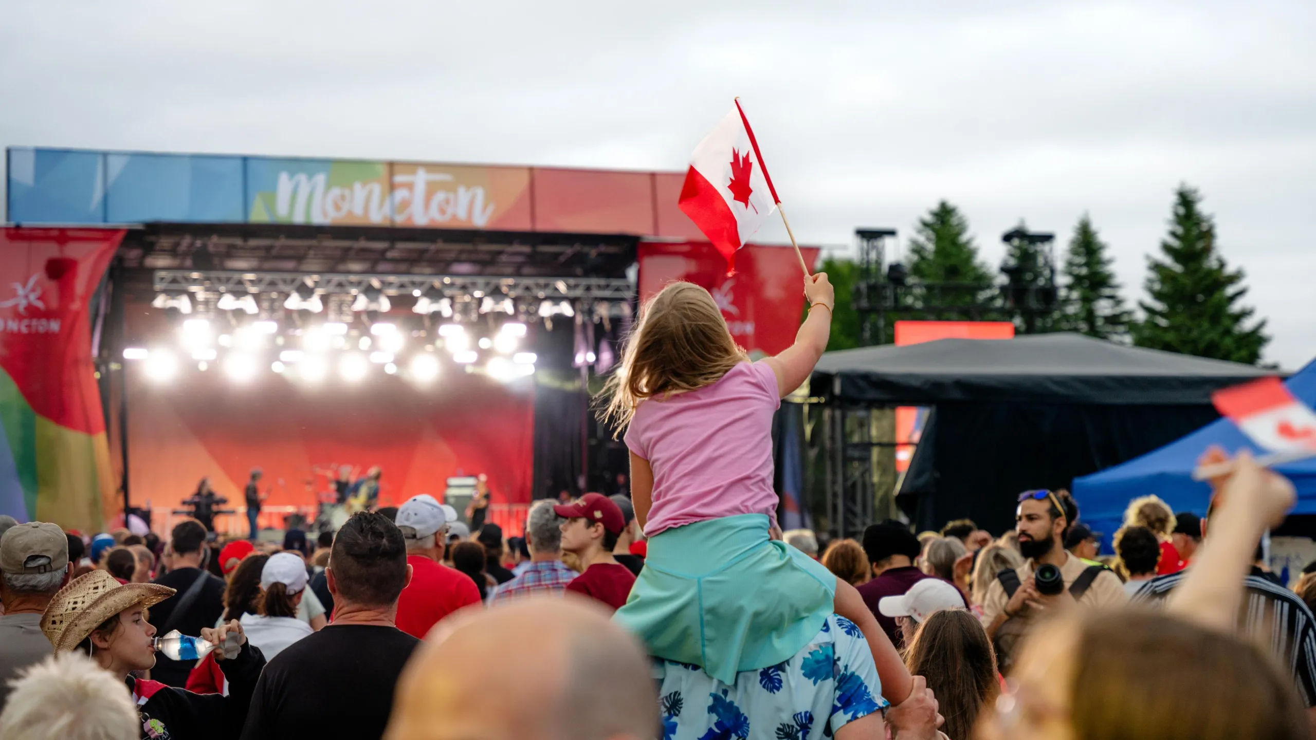 A child waving a Canadian flag in the audience of a concert 