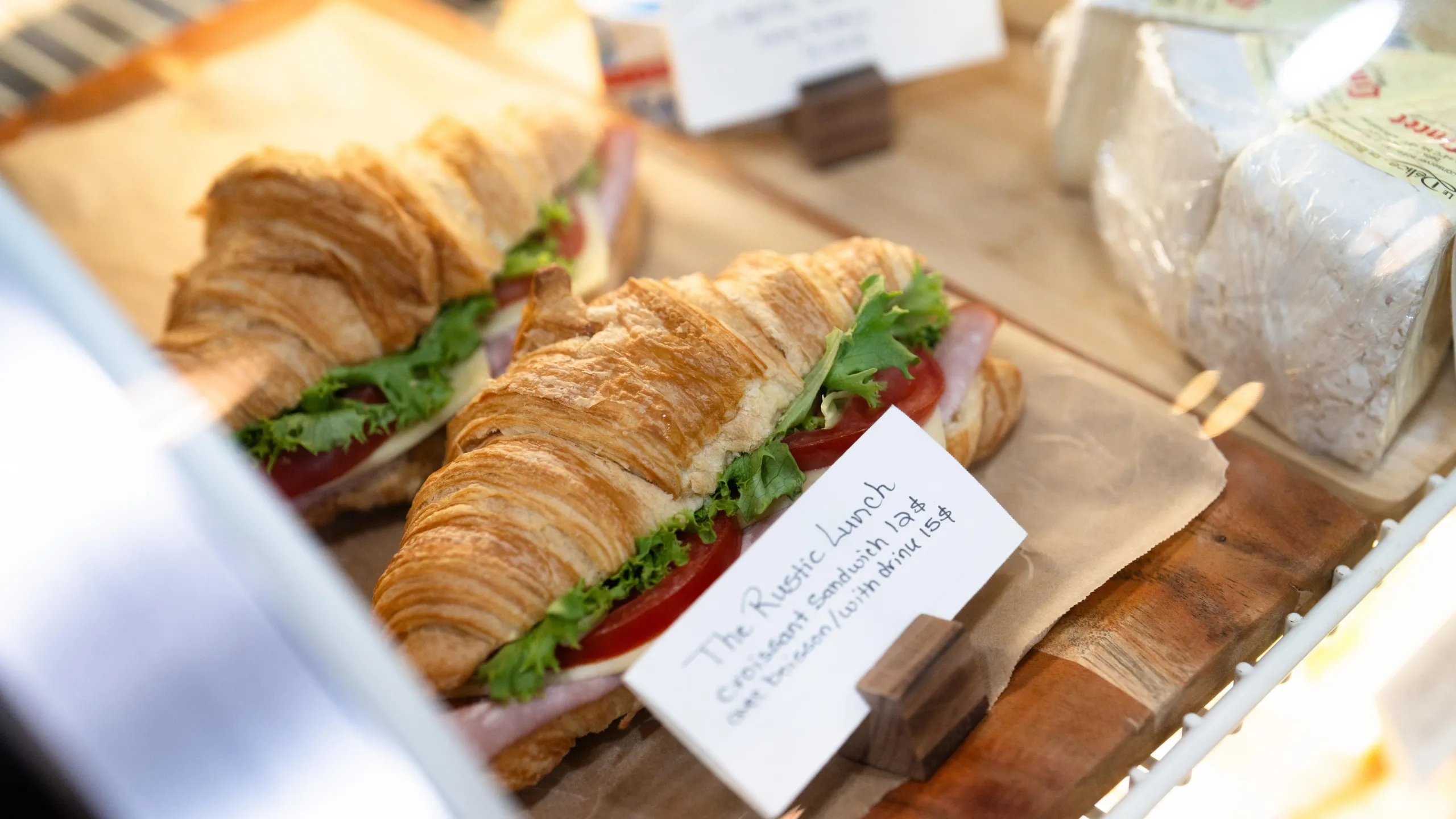 A row of croissant sandwiches for sale on a tray.