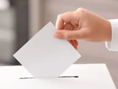 Hand dropping a ballot into a box