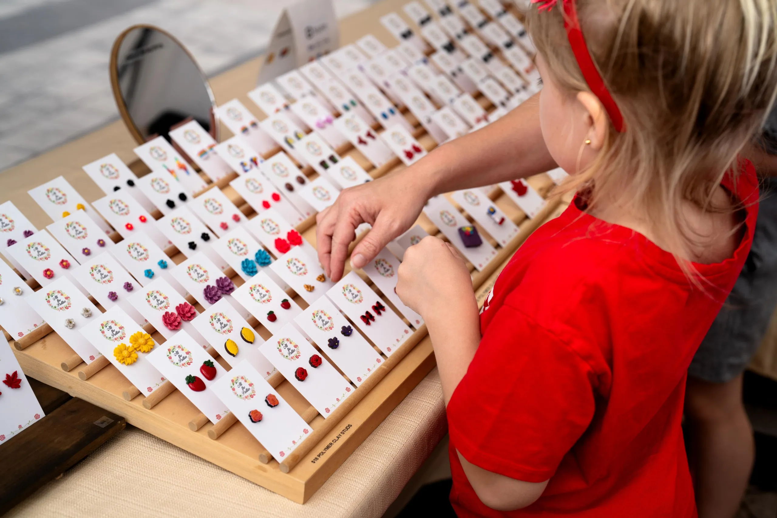 Child looking at earrings at the artisan village on Downing Street for Canada Day