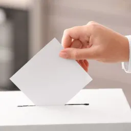 Hand dropping a ballot into a box